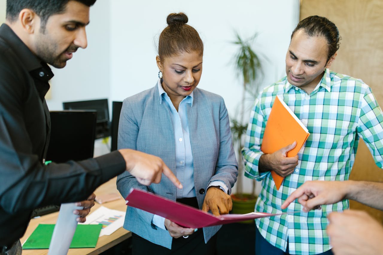 A group of professionals discussing documents in an office meeting, showcasing teamwork and collaboration.